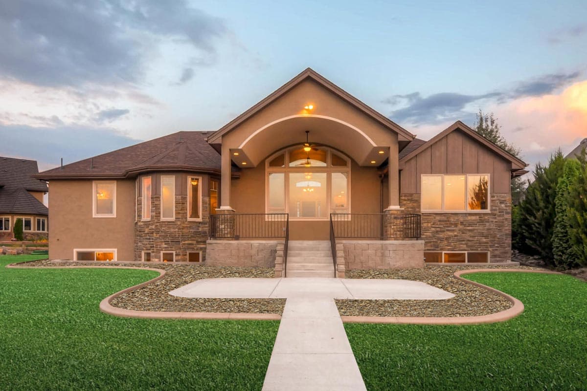 House plan exterior with stucco and stone facade, arched entryway, multi-story design, and large windows.