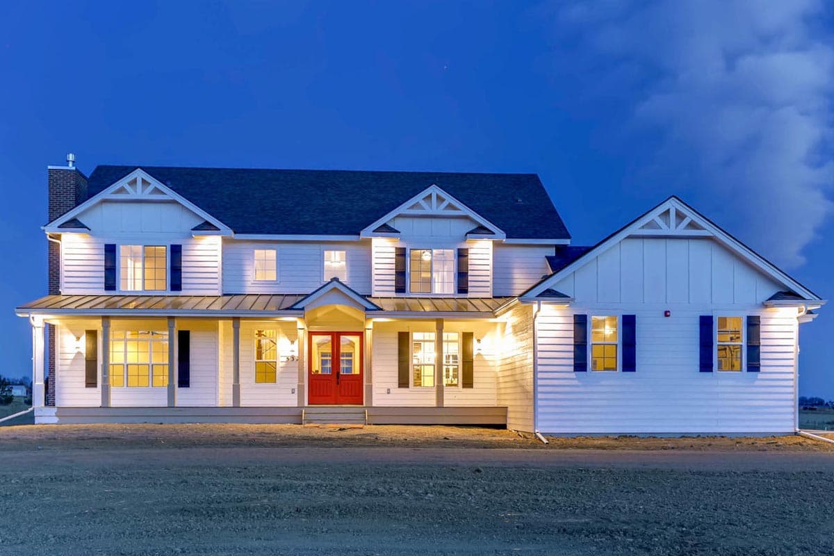 House plan exterior with two stories, a farmhouse style, a covered front porch, gables, and dark shutters. Red front door is visible.