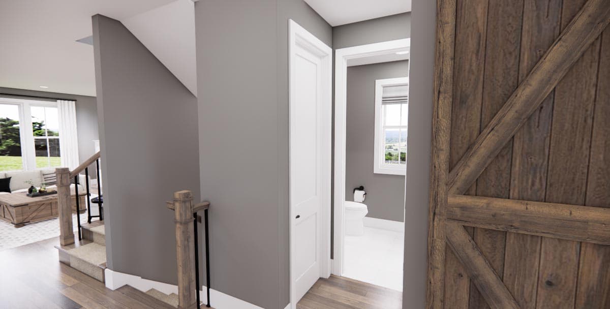 Interior view of house with staircase, barn door, and view into a bathroom with toilet and window.