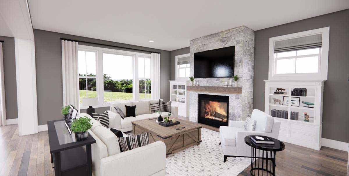 Living room with stone fireplace, television, large windows, white sofas, and built-in shelving.