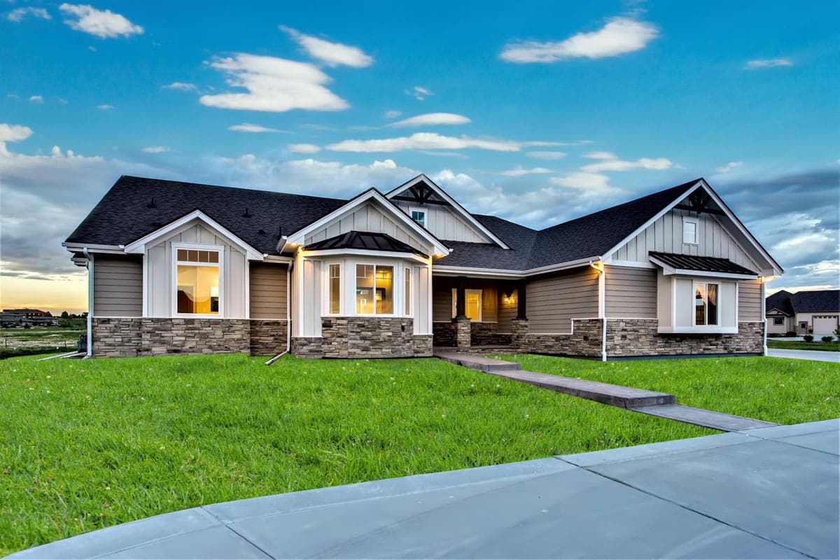 House plan exterior of a one-story Modern Farmhouse with stone and siding, gables, and bay windows.