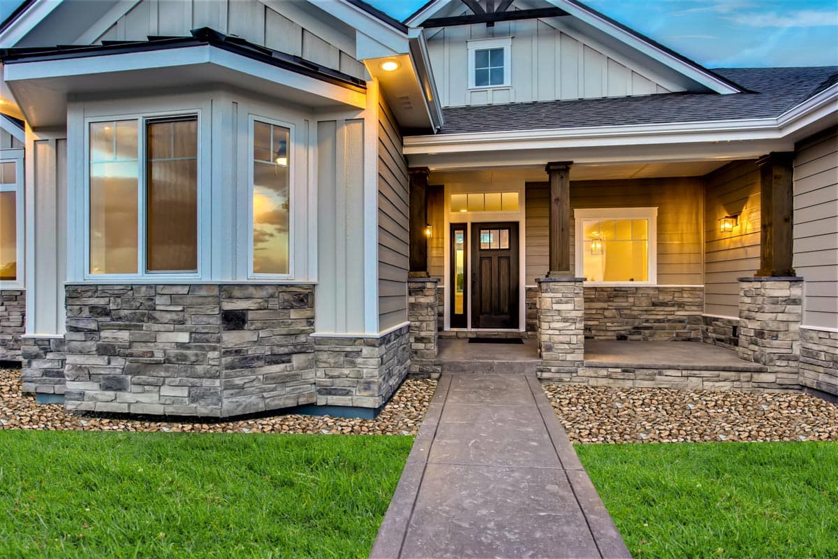 House plan exterior showing a covered porch with stone accents, bay window, board-and-batten siding, and gabled roof.