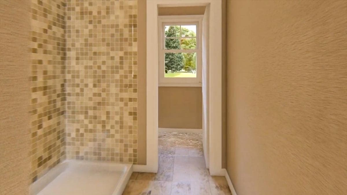 Interior view of a bathroom with mosaic tile shower and a window overlooking trees.