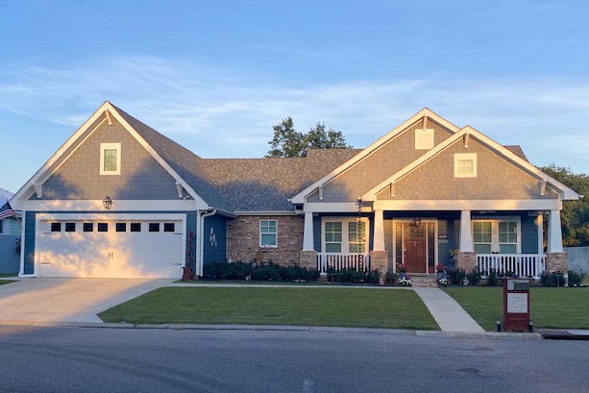 Craftsman style house plan exterior: one story, gabled dormers, covered porch with stone pillars, and attached two-car garage.