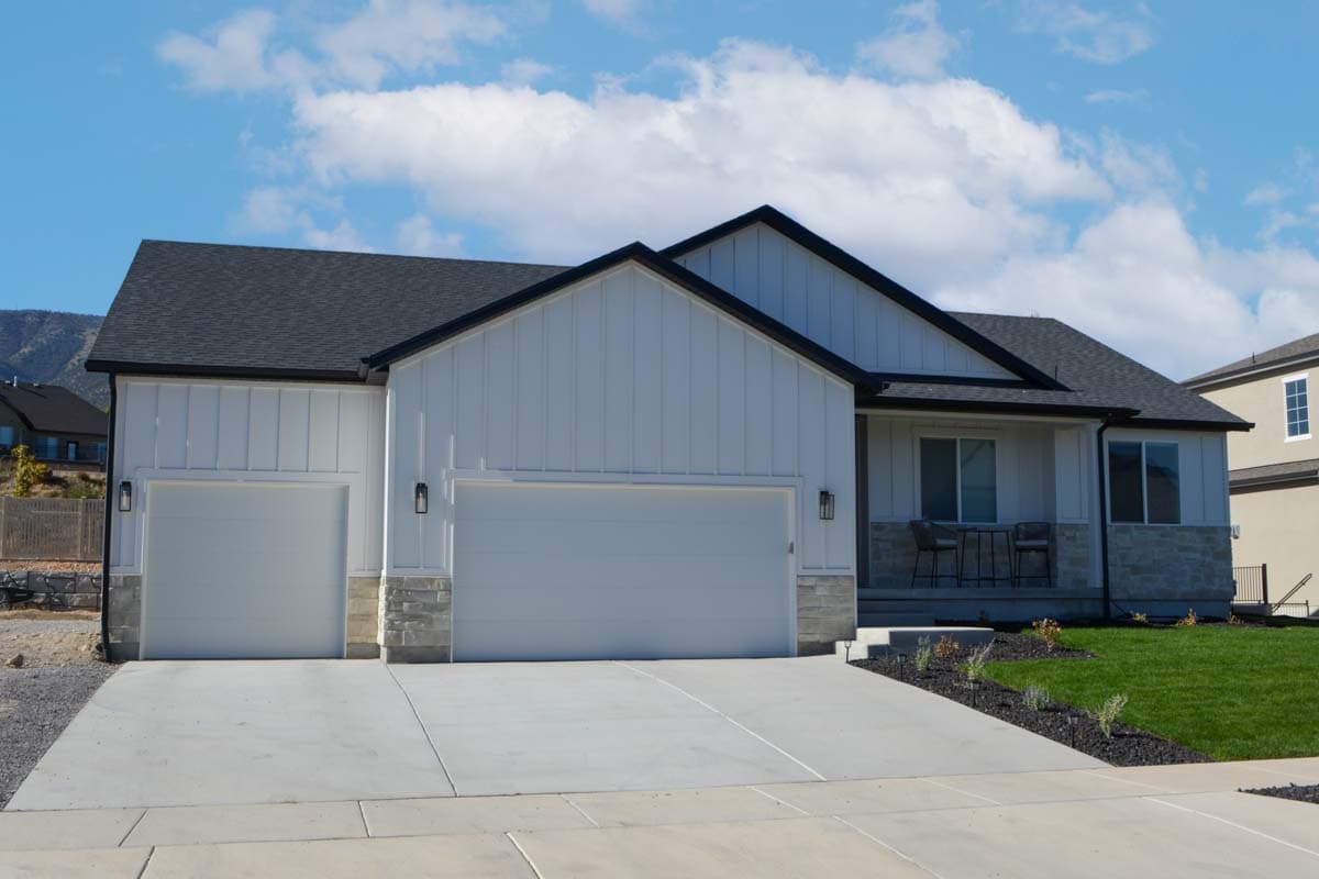 House plan exterior: Modern Farmhouse style, one story, white vertical siding, stone base, dark roof, double garage, and covered entry.