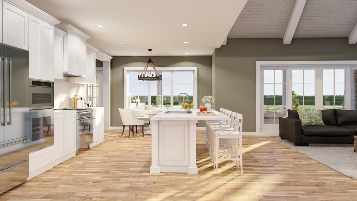 Open concept kitchen with large island and seating, dining area, and living room with sectional sofa and large windows.
