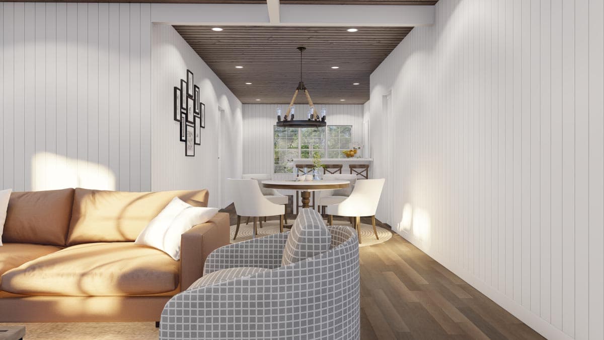 Interior view showing a living area with sofa, dining area with round table, and kitchen island with bar seating.