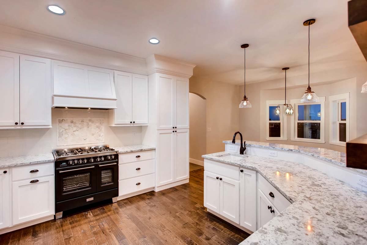 Kitchen with white cabinetry, granite countertops, a black range, and a bay window.