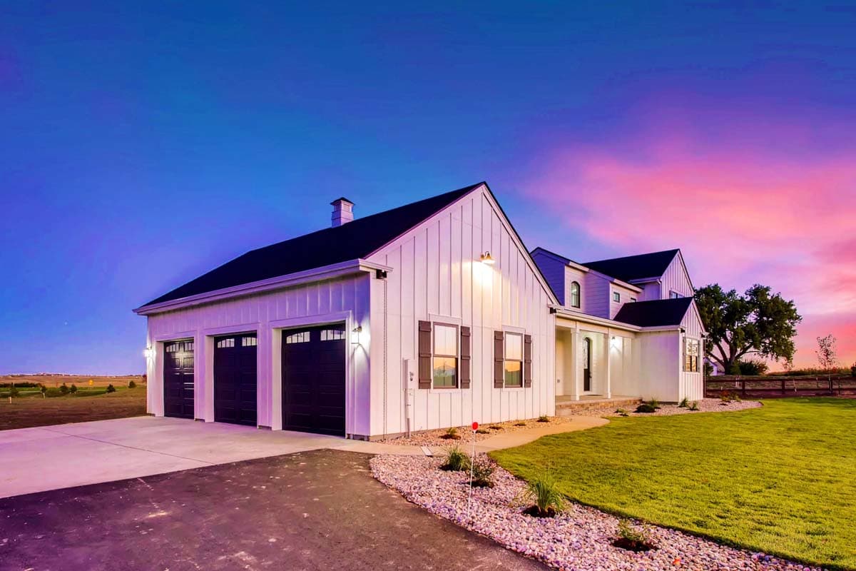 Modern Farmhouse house plan exterior with white vertical siding, a three-car garage, gables, and a covered entry.