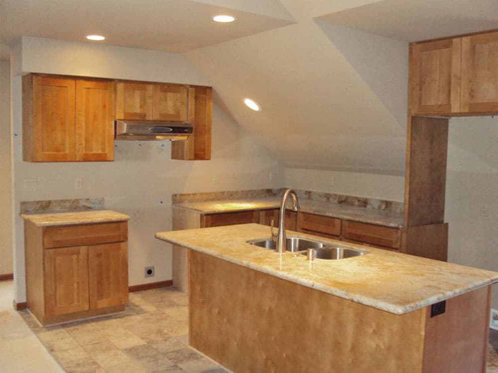 Kitchen featuring light wood cabinets, granite countertops, and an island with a double sink.