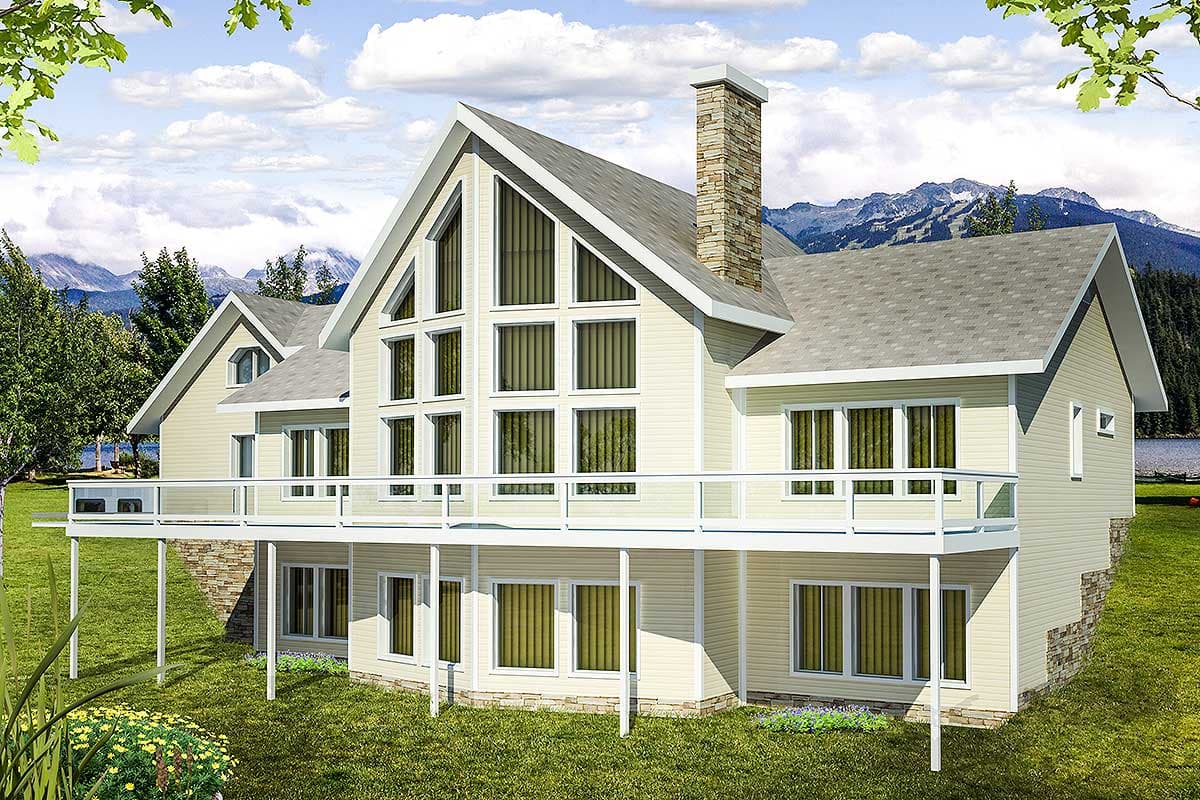 House plan exterior with gable roof, large window wall, stone chimney, and two-story raised deck. Mountain view in background.