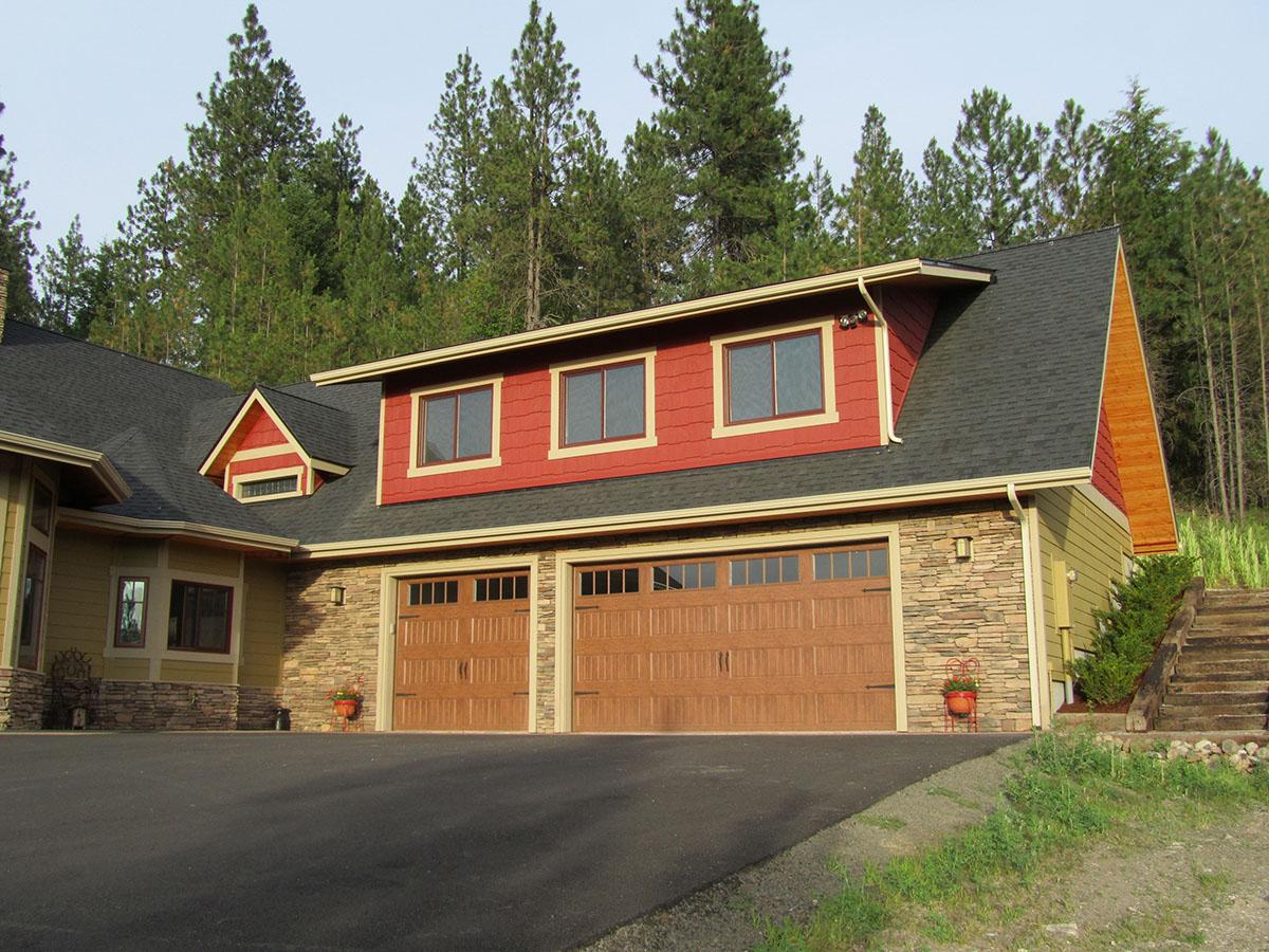 House plan exterior: Two-story home with stone and siding, dormer, and attached three-car garage.