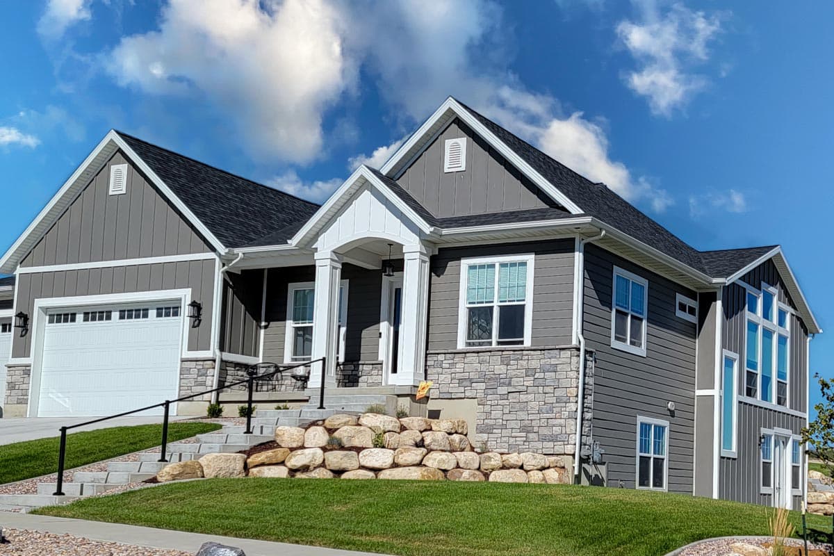 House plan exterior featuring a two-story Modern Farmhouse style with gabled roofs, a covered entrance with columns, and stone accents.
