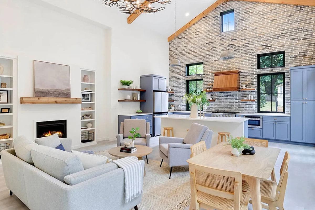 Interior rendering of an open-concept living and kitchen area with vaulted ceilings, fireplace, kitchen island, and blue cabinetry.