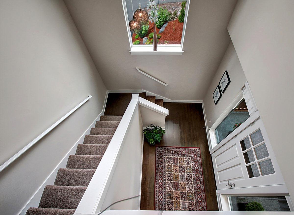 Interior view of a staircase with a large skylight, dark wood floors, and a patterned rug.