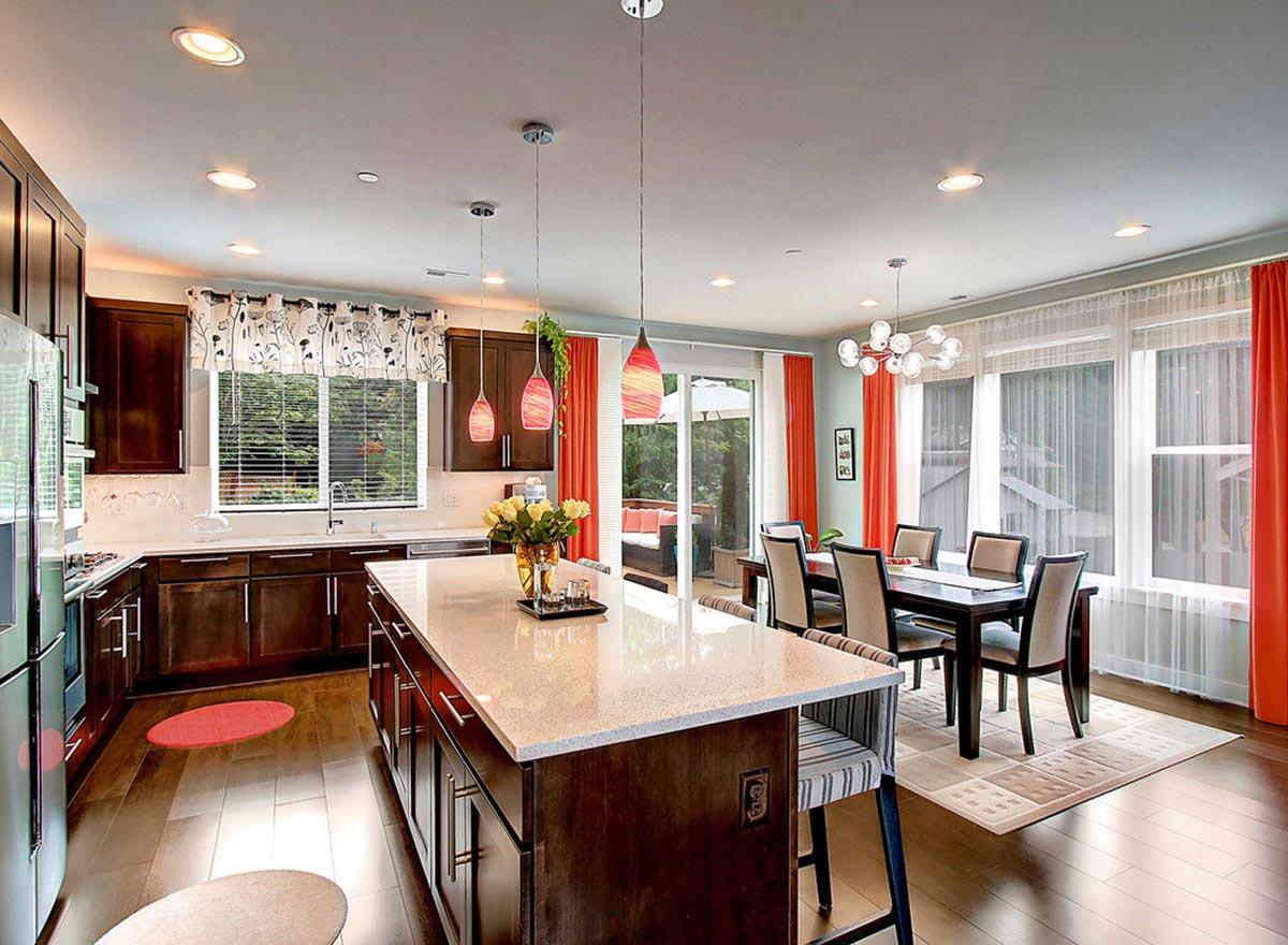 Open-concept kitchen and dining area with large island, dark wood cabinets, and sliding glass doors to a patio.