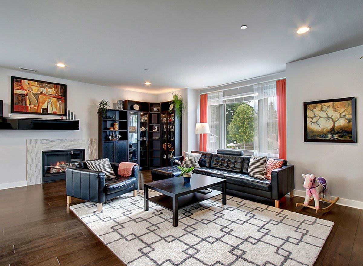 Living room with fireplace, L-shaped sectional sofa, accent chairs, coffee table, and display cabinets.
