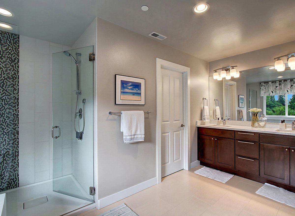 Bathroom with glass-enclosed shower featuring mosaic tile, double vanity with dark wood cabinets, and large mirror.