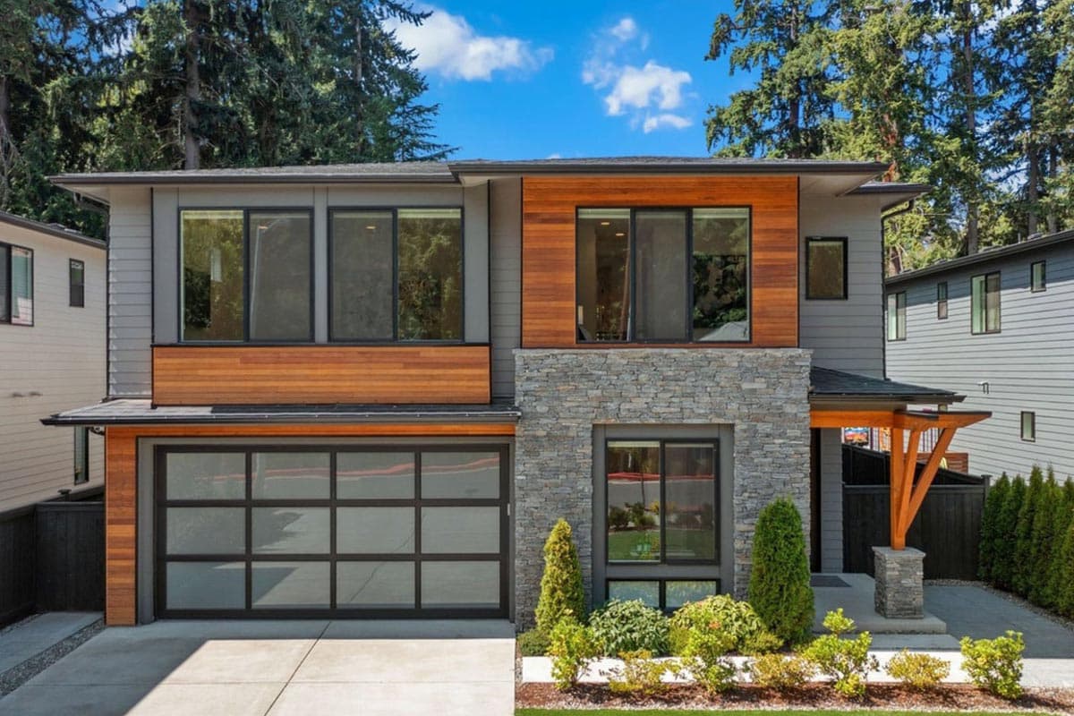 Two-story house plan exterior with modern style, stone and wood facade, glass garage door, and cantilevered rooflines.