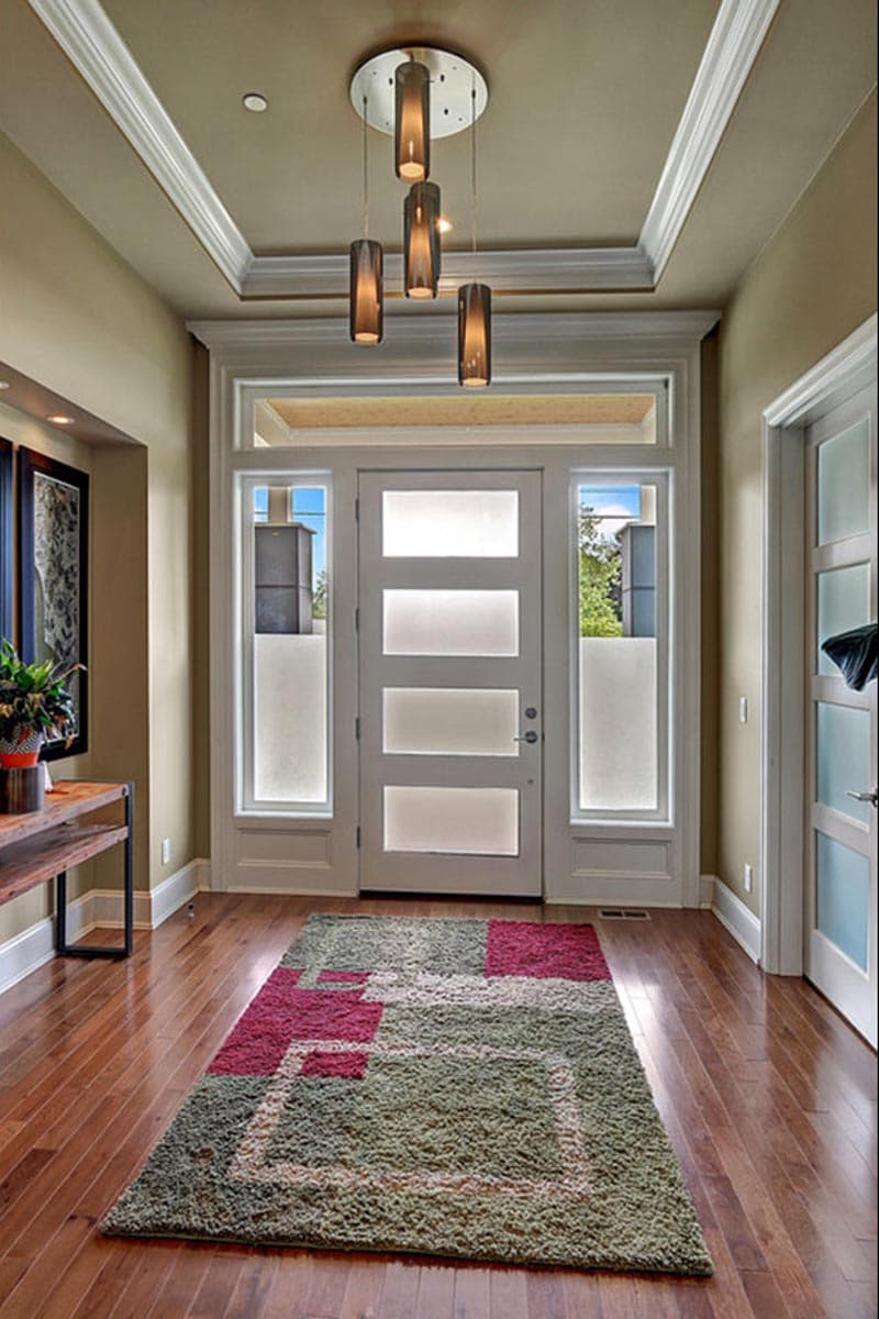 Modern entryway with frosted glass sidelights flanking a four-panel frosted glass door, decorative ceiling light fixture.