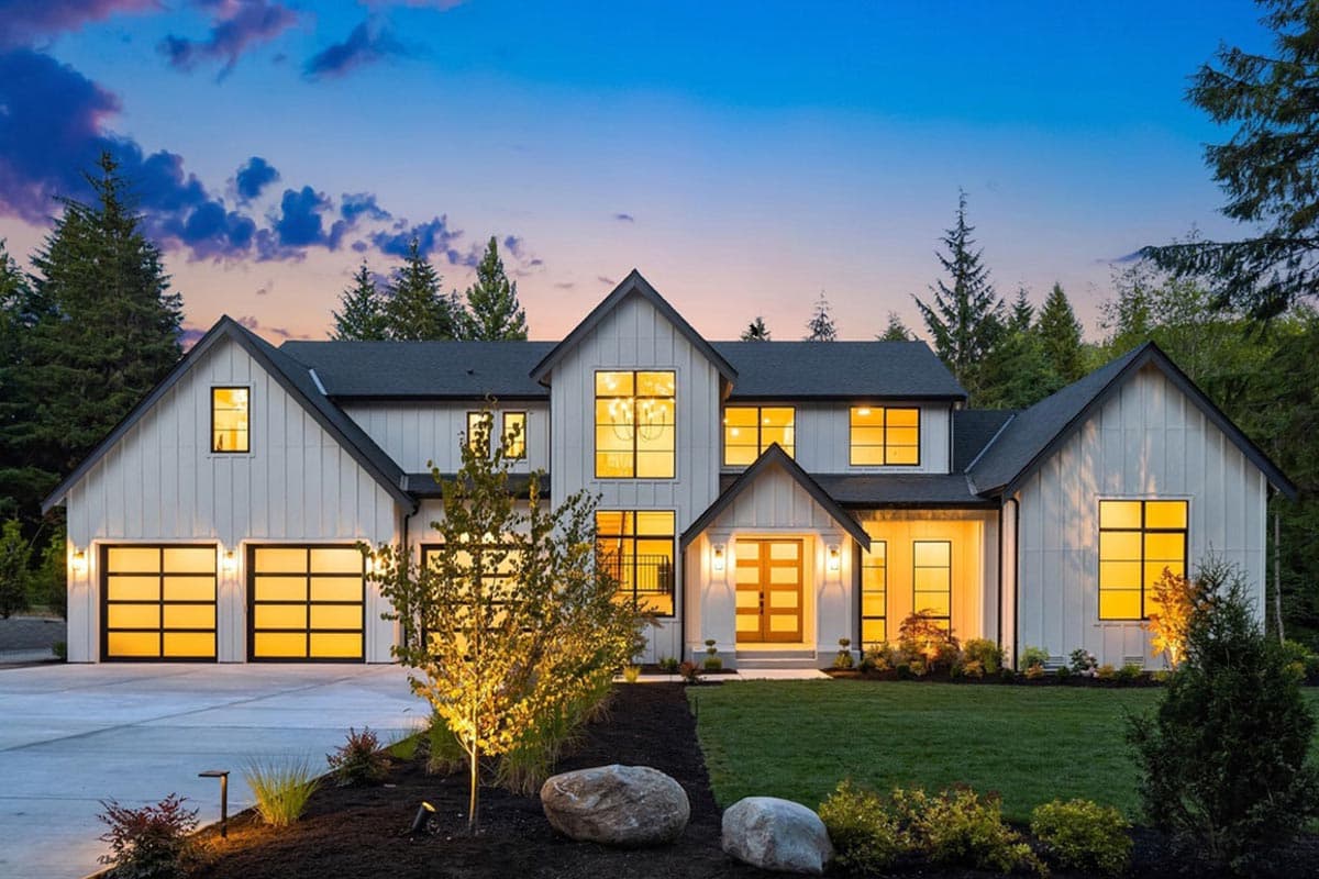 House plan exterior. Two-story Modern Farmhouse with gabled roof, two-car garage, and covered entry. Large windows and horizontal siding are visible.