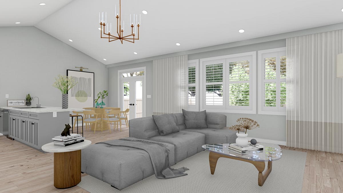 Open-concept living space with vaulted ceiling, kitchen island, dining area, and living room with sectional sofa and large windows.