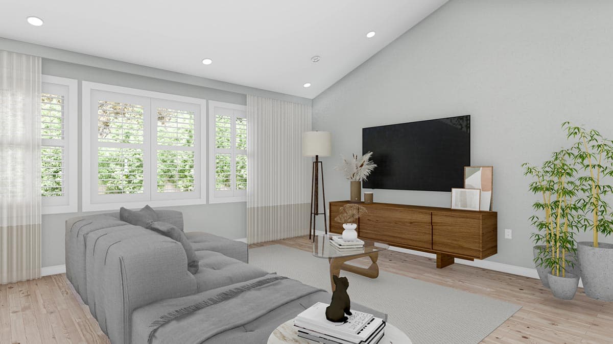 Living room with vaulted ceiling, sectional sofa, media console, and large windows with plantation shutters.