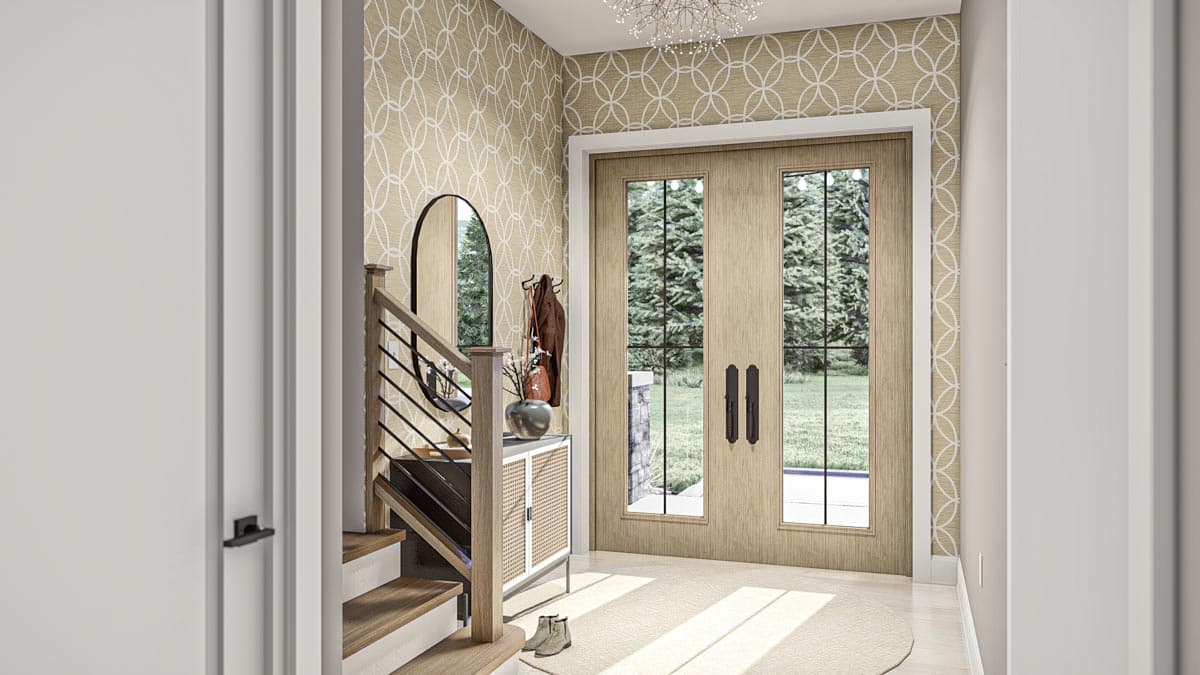Entryway with wood double doors, staircase, patterned wallpaper, and an oval mirror.