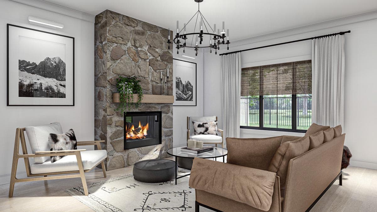 Living room with stone fireplace, modern chandelier, wood-framed chairs, and large windows.