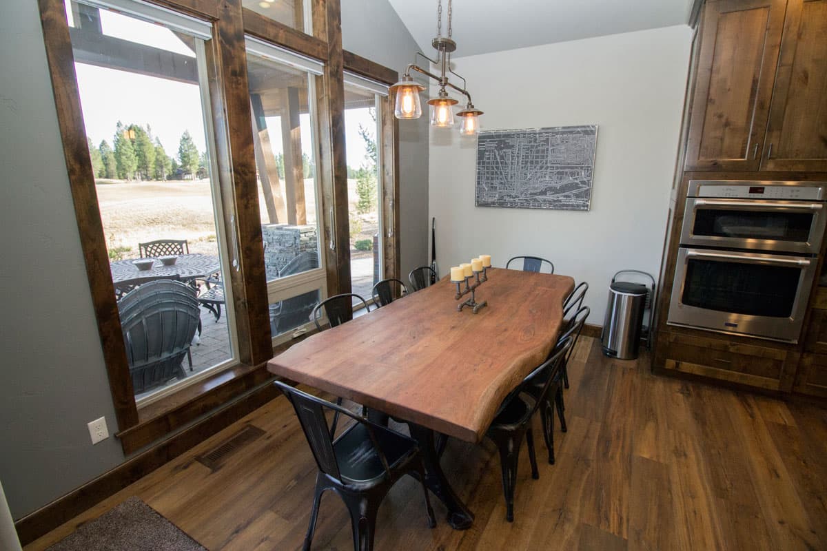 Dining room with live-edge wood table, seating for eight, large windows, and built-in double oven.
