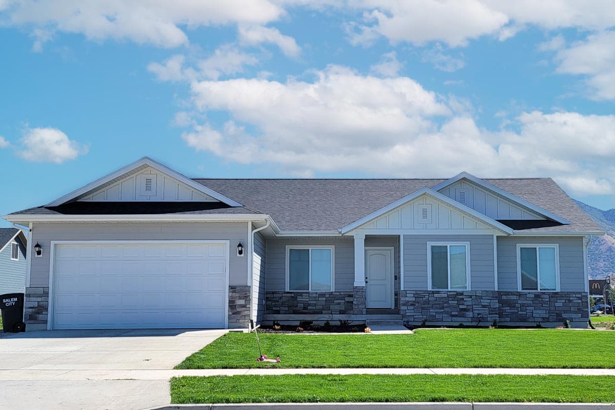 House plan exterior. One-story house with gabled roof, stone veneer on the lower portion of the facade, and an attached garage.