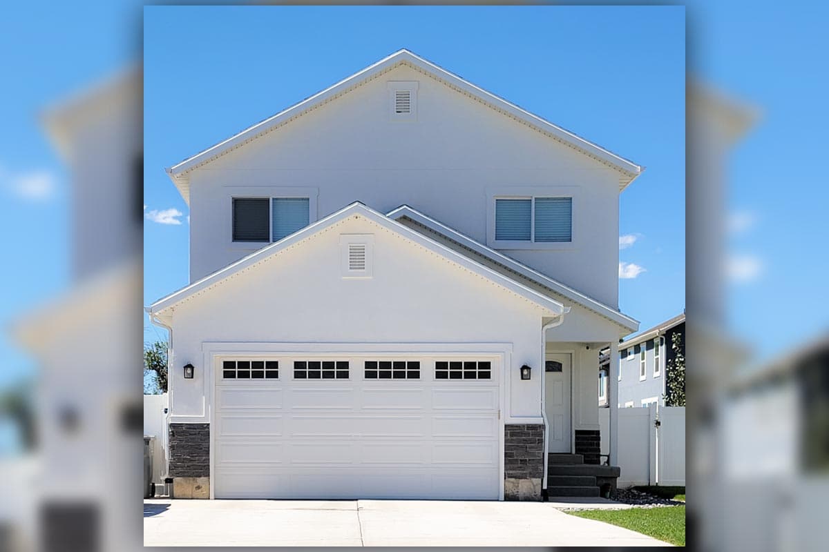 House plan exterior featuring a two-story design with a gable roof, garage, and symmetrical window placement, with a covered porch.