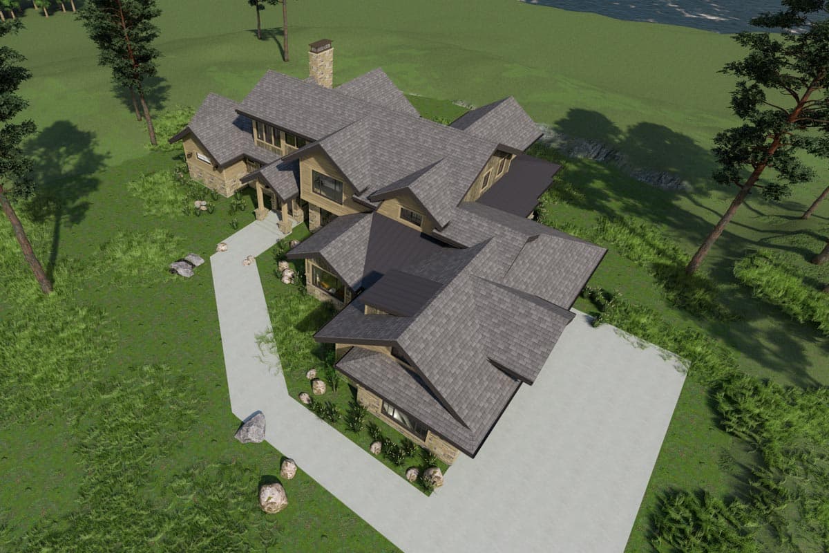 An aerial view of a large, modern house with multiple roof lines, a long driveway, and surrounding green landscape.