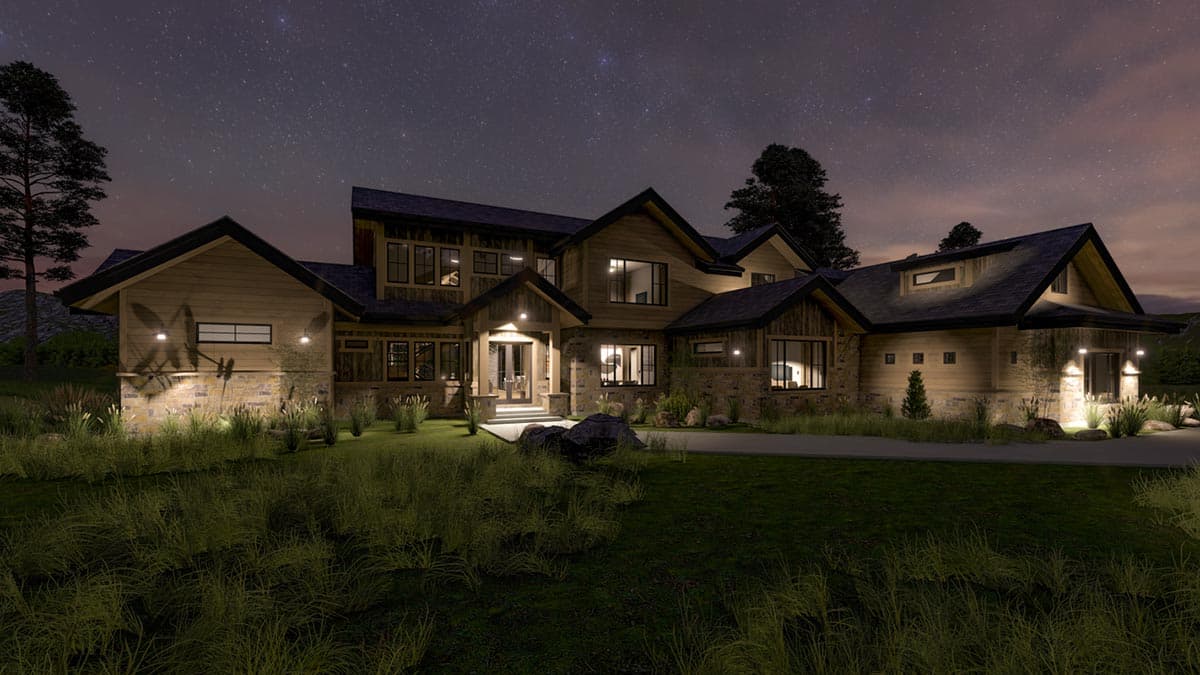 A large, multi-level home at night. Exterior lights illuminate the stone and wood siding, contrasting with the dark sky filled with stars.