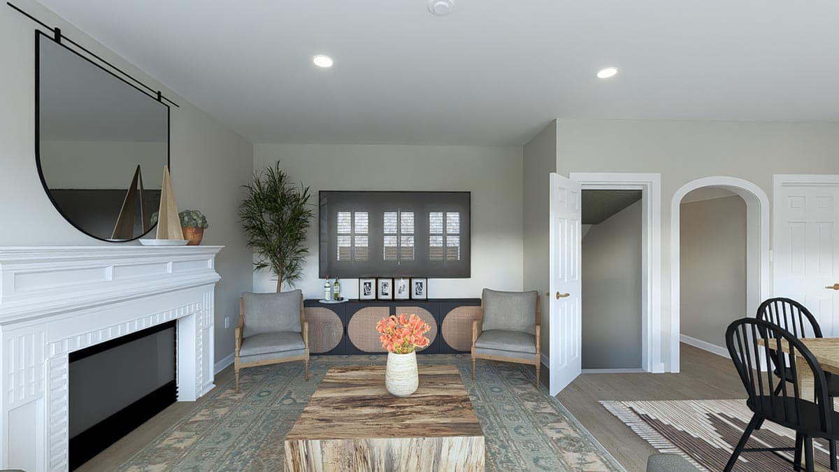 Living room with fireplace, vaulted ceiling, and an open doorway leading to a staircase and dining area.
