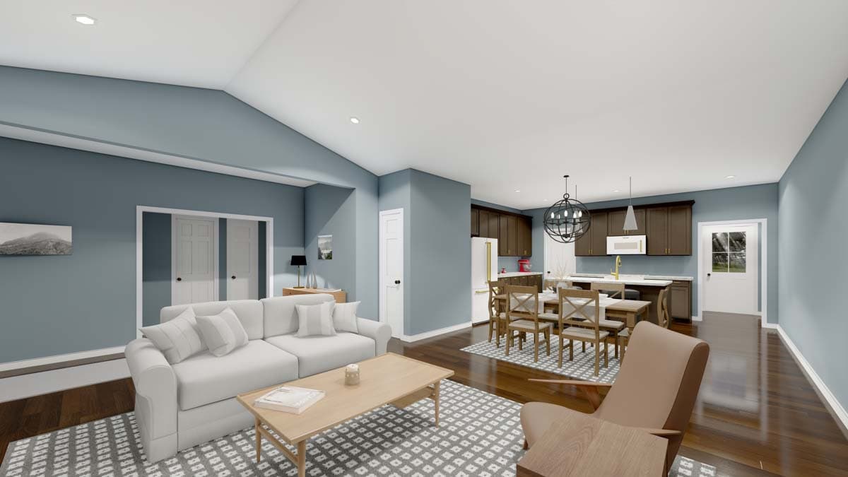 Open-concept living area with vaulted ceiling, sofa, dining table, and kitchen with dark wood cabinets.