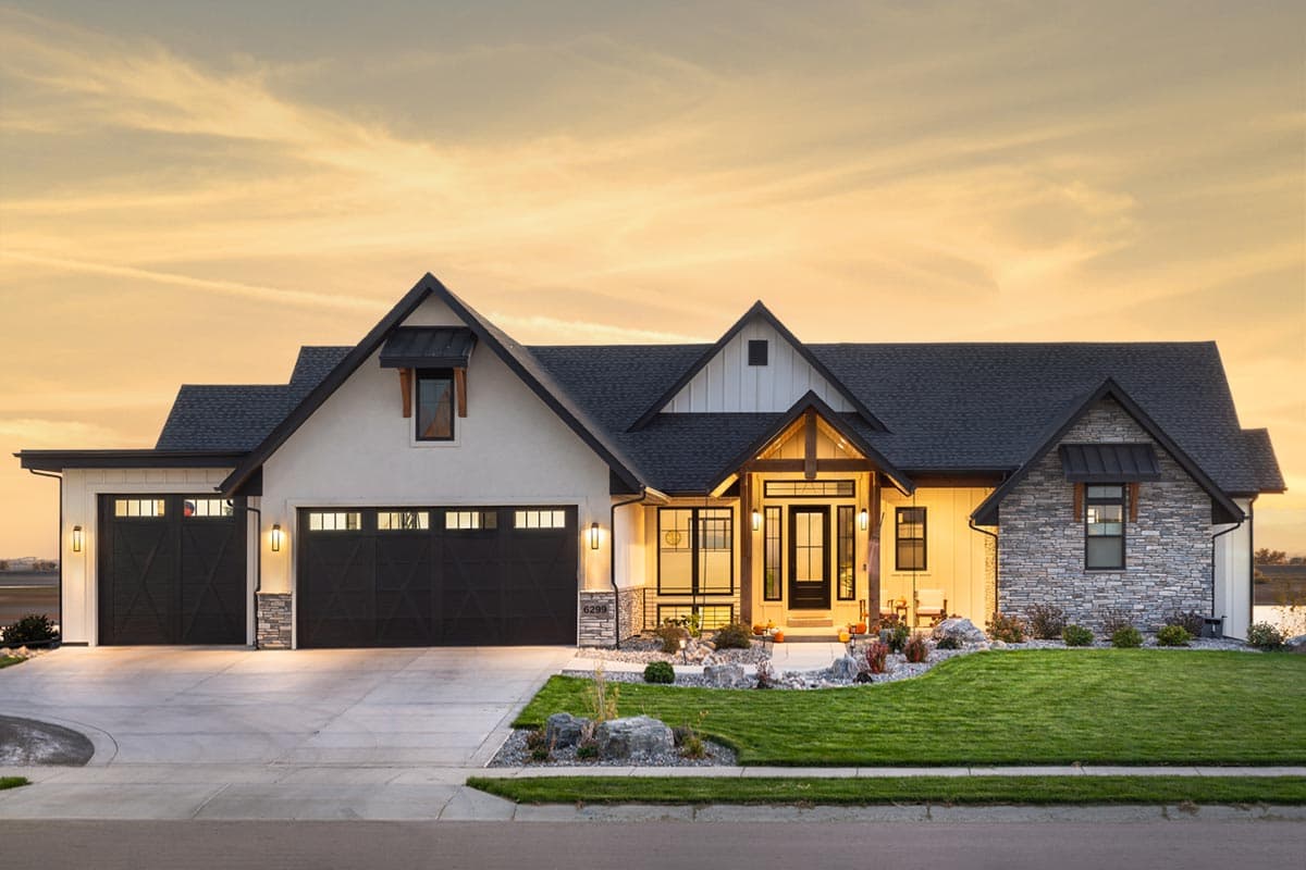 House plan exterior. Modern farmhouse style with gabled roof, two-car garage, and stone accent. Features include covered porch and shed-style dormers.