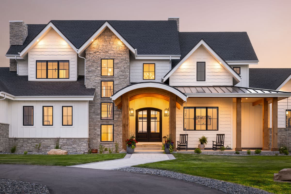 Modern Farmhouse house plan exterior with stone accents, gables, arched entryway, and multiple dormers.