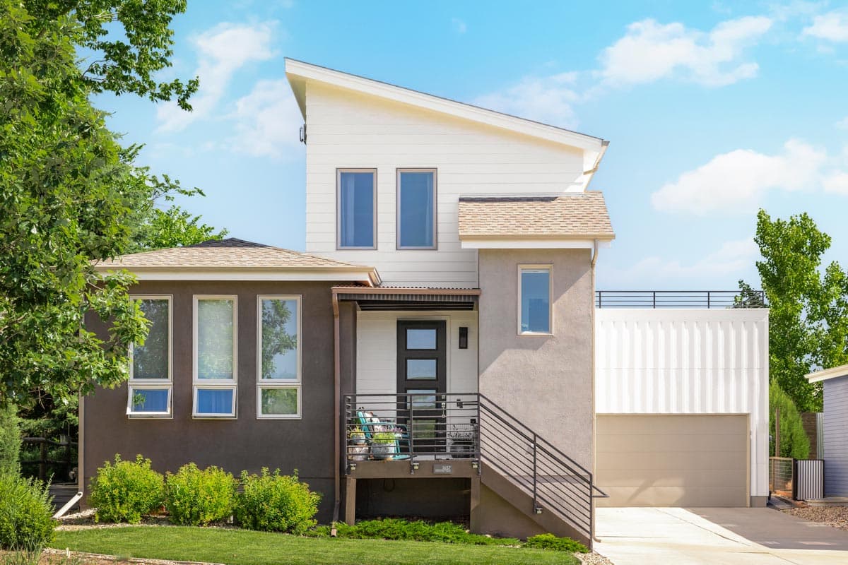 House plan exterior. Two-story Modern house with a shed roof, a covered entry porch, and a detached garage with a flat roof and balcony.