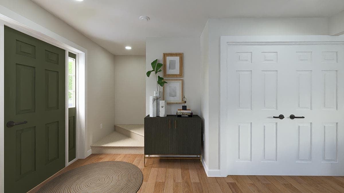 Interior view of an entryway showing a green paneled door, a dark cabinet, and a carpeted staircase leading upwards.