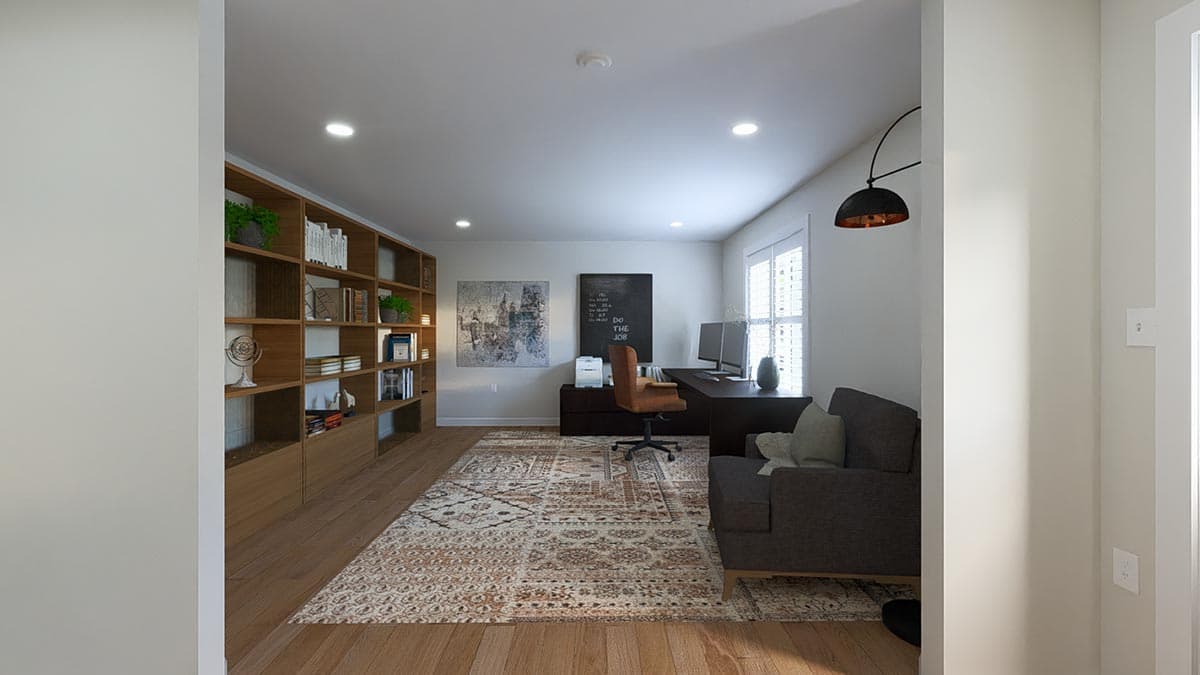 Home office with built-in shelving, a desk with dual monitors, office chair, and a sofa.