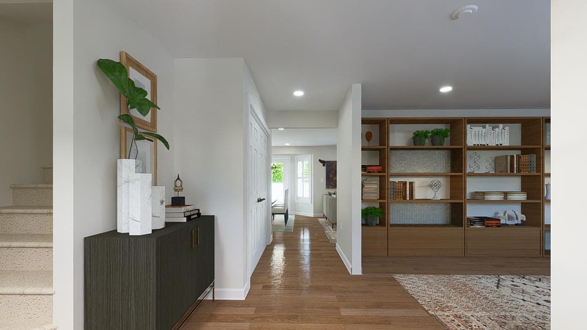 Interior view showing a hallway with a carpeted staircase, dark wood cabinet, and built-in bookshelves.