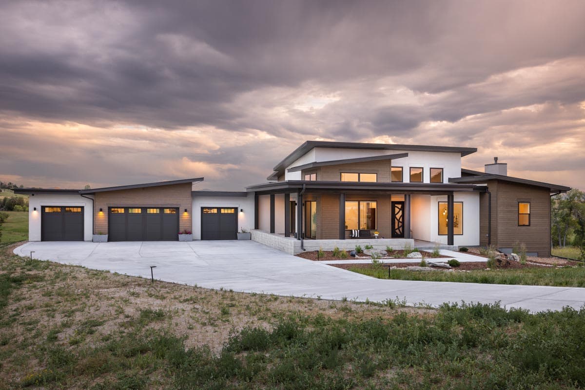 House plan exterior. Modern style with flat and angled rooflines, covered porch, and attached three-car garage. Features wood and white siding.