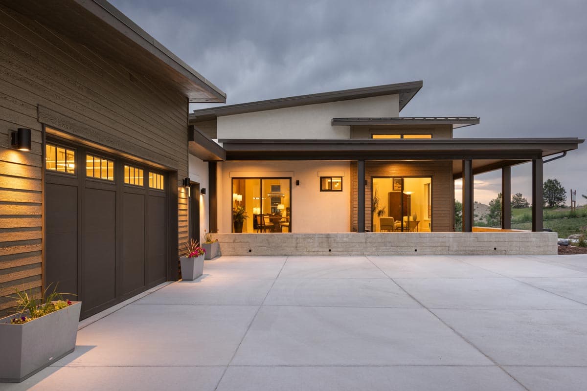 Modern house plan exterior with horizontal siding, multi-level roof, covered patio, and a three-car garage.
