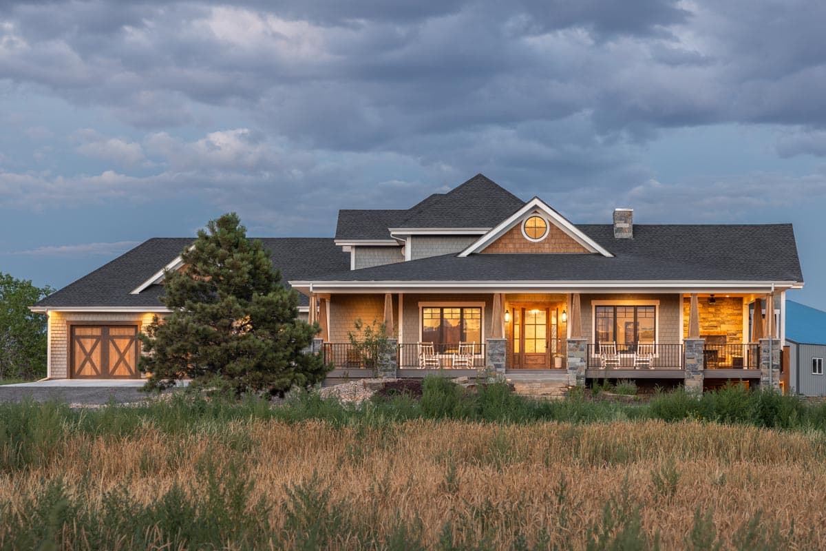 House plan exterior with Craftsman-style elements. Features include a front porch, gables, and a stone chimney. Two-story with a garage on the left.