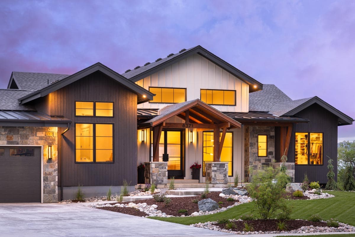 Modern house plan exterior with stone accents, dark siding, white board-and-batten, and a covered wood-beam entry.