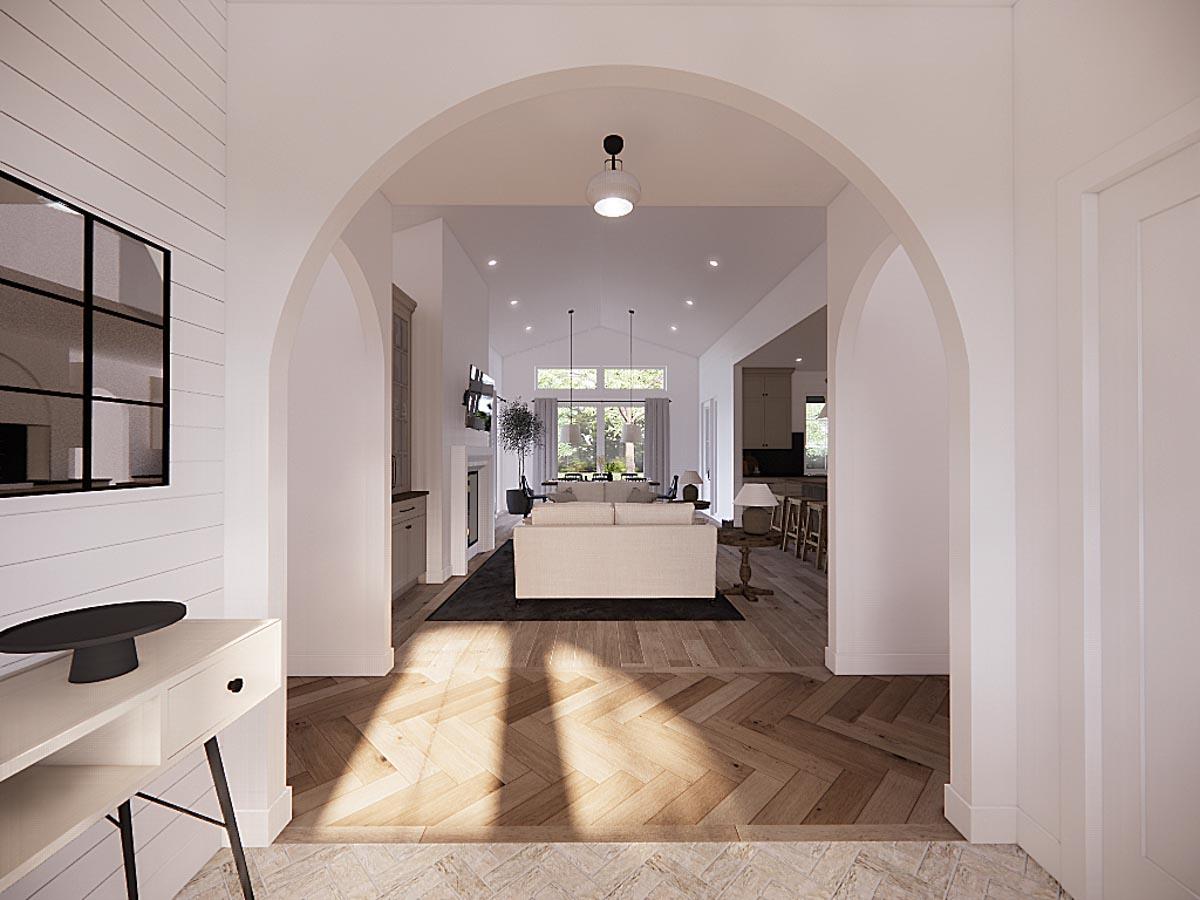 A hallway opens into a living space, framed by an archway and hardwood floors, leading to a modern, open-concept home interior.