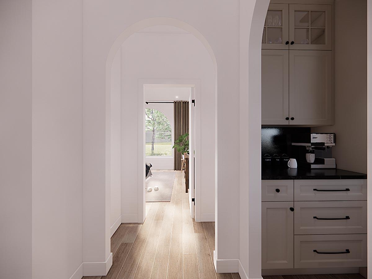 A hallway with arched doorways leads the eye to a sunlit room. On the right, a built-in coffee station with cabinets is visible.