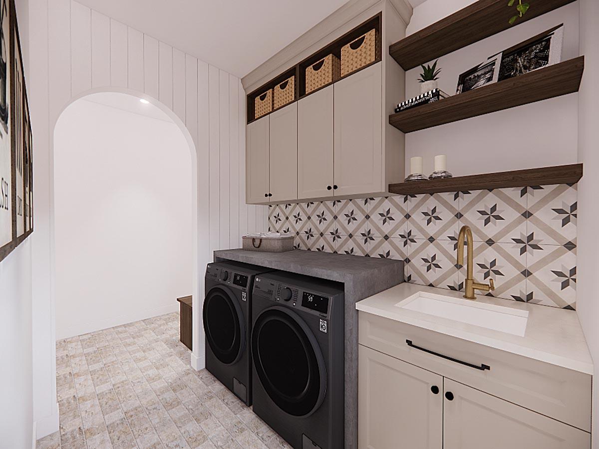 A modern laundry room featuring a washer and dryer, cabinetry with woven baskets, and patterned tile backsplash with a white sink and golden faucet.