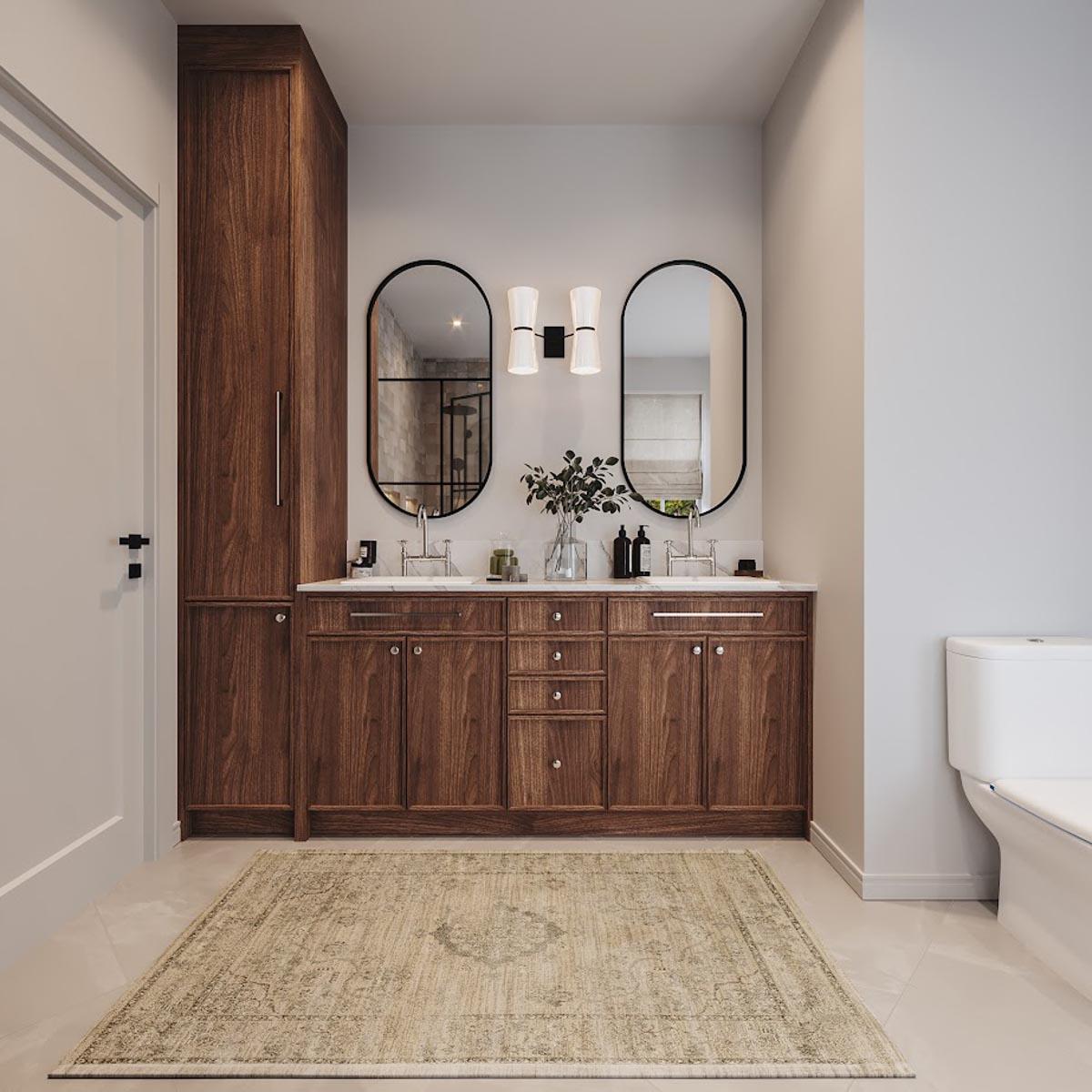 Bathroom with double vanity, dark wood cabinets, marble countertop, oval mirrors, sconce lighting, and a tall linen cabinet.